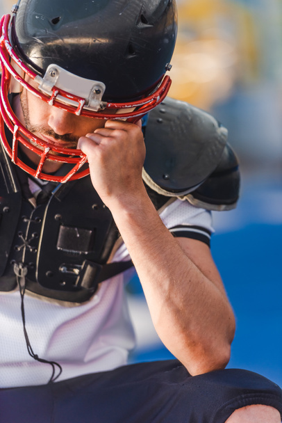 jonge american football speler kooi van helm te houden tijdens de vergadering op sportstadion - Foto, afbeelding