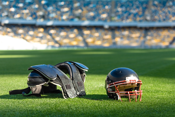 casque de football américain avec protection thoracique couché sur l'herbe verte du stade
 - Photo, image