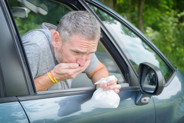 Člověk trpící mořskou nemoc v autě a drží sáček při nevolnosti - Fotografie, Obrázek