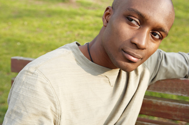 attractive african american man being thoughtful while sitting on a bench in a park. - Foto, immagini