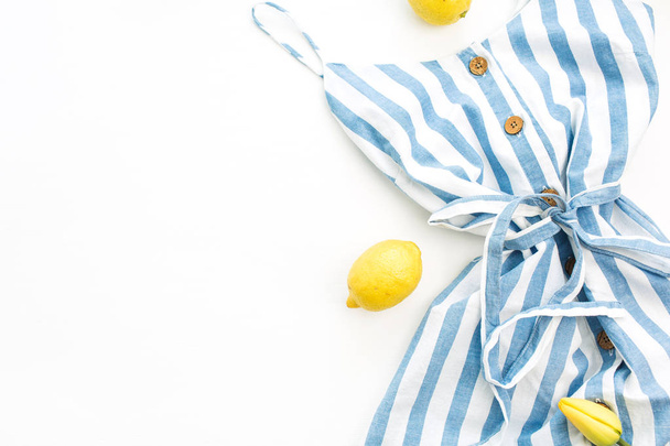 Sommer Damenmode stilvolle Komposition. Kleid und Zitronen auf weißem Hintergrund. flache Verlegung, Draufsicht minimales Konzept. - Foto, Bild