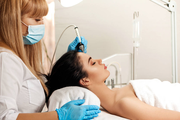 Beautician makes cleaning of face in spa salon. - Zdjęcie, obraz