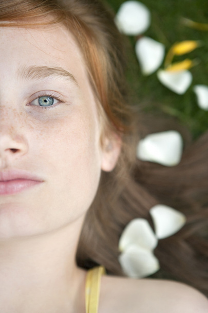 Portret van tienermeisje vaststelling van op gras en bloemblaadjes close-up. - Foto, afbeelding