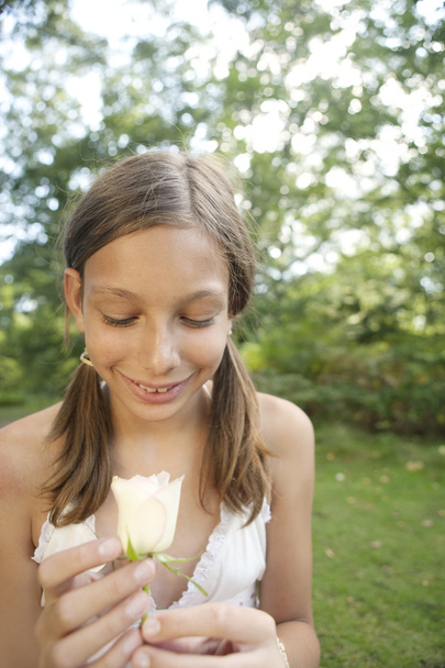 tienermeisje kijken naar een witte roos - Foto, afbeelding