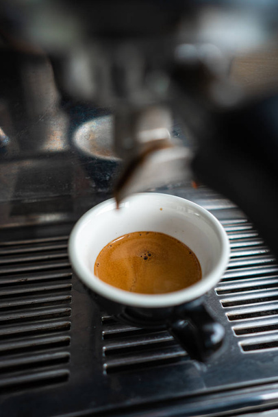 Klein kopje espresso staande in de stalen koffiemachine - Foto, afbeelding