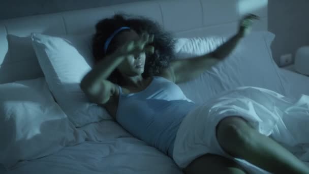 Ideges fekete nő ébren a nyári melegben az ágyban - Felvétel, videó