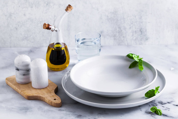 Empty set of plates for soup on a table with spices and olive oil in a decanter. - Fotó, kép