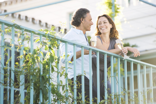 Casal maduro bebendo champanhe enquanto se inclina na varanda de um hotel ao ar livre
. - Foto, Imagem