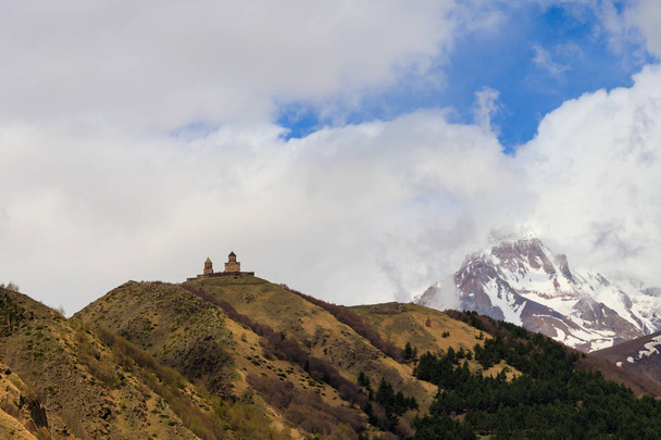 Vista sobre el monte Kazbek y la iglesia de la Trinidad de Gergeti (Tsminda Sameba), iglesia de la Santísima Trinidad cerca del pueblo de Gergeti en las montañas del Cáucaso, Georgia
 - Foto, imagen