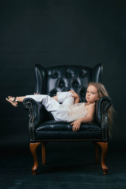 Chica posando en una silla de cuero negro
 - Foto, imagen