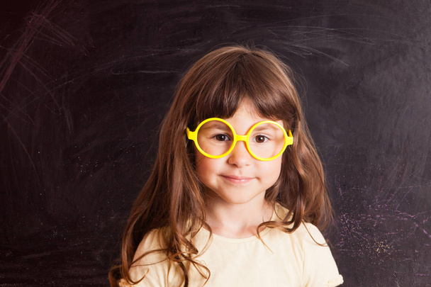 Happy little girl schoolgirl from the blackboard - Фото, изображение