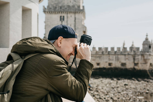 A professional photographer or a young male tourist photographes the sights in Lisbon in Portugal. Leans the camera to his head and laughs. Very satisfied with the photo - Photo, Image