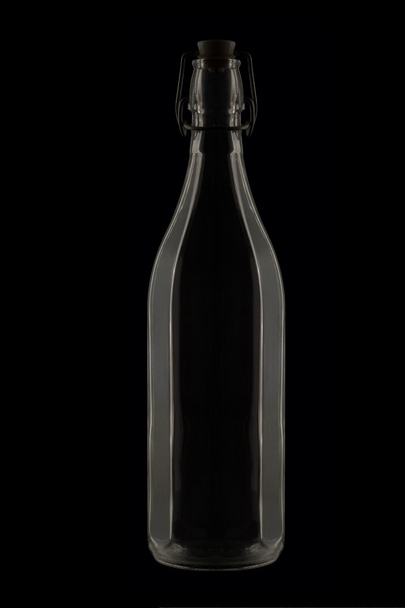 glazen fles tegen een zwarte achtergrond, low-key afbeelding - Foto, afbeelding