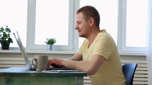 succesvolle gelukkig freelancer werkt thuis aan tafel met laptop en de camera kijken - Video