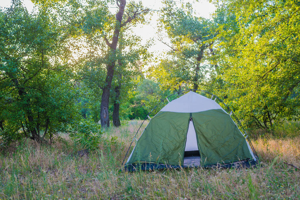 Concept of outdoor activities, a tent and a fire in a forest glade. Tourism, rest with a tent. - Foto, afbeelding