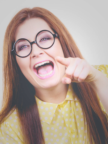 Happy cheerful young adult woman with long brown hair and nerdy big eyeglasses gesturing pointing with her fingers. - Fotoğraf, Görsel