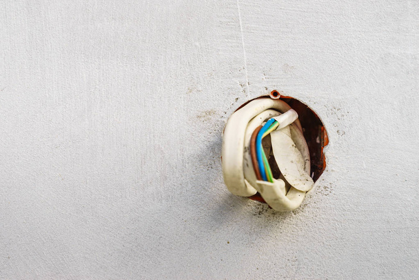 Colorful cables wires sticking out of grey concrete wall. Details during house renovations. - Foto, Imagem