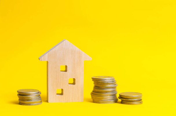 coins and wooden house on a yellow background. Concept of real estate. Buying, selling and renting a house. Loan for an apartment, mortgage rate. Affordable housing for young families. - Φωτογραφία, εικόνα