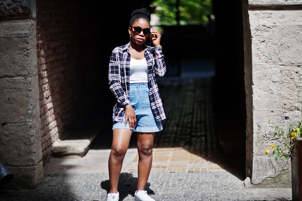 Hip hop african american girl on sunglasses and jeans shorts. Casual street fashion portrait of black woman. - Valokuva, kuva