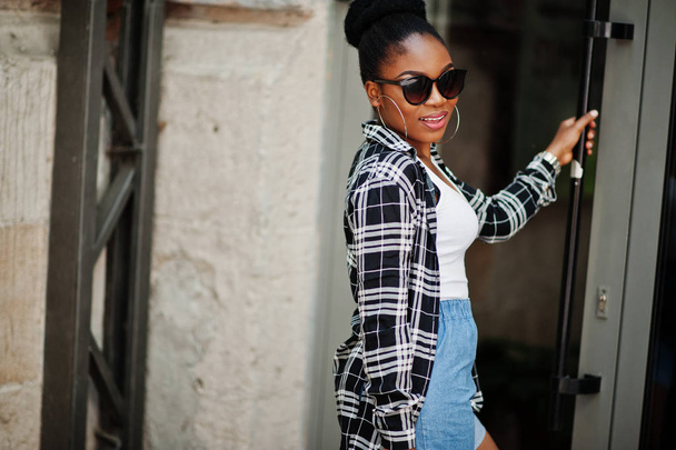 Hip hop african american girl on sunglasses and jeans shorts. Casual street fashion portrait of black woman. - Fotó, kép