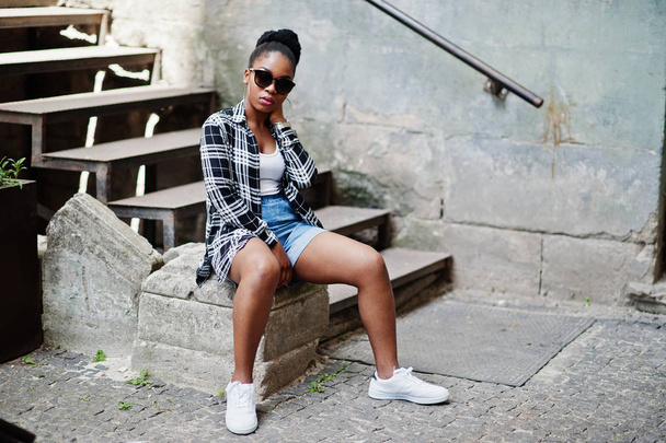 Hip-Hop-Afroamerikanerin mit Sonnenbrille und Jeans-Shorts. Casual Street Fashion Porträt einer schwarzen Frau. - Foto, Bild
