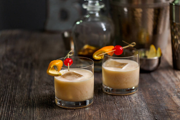 Whiskey sour cocktail garnished with orange and cherry. - 写真・画像