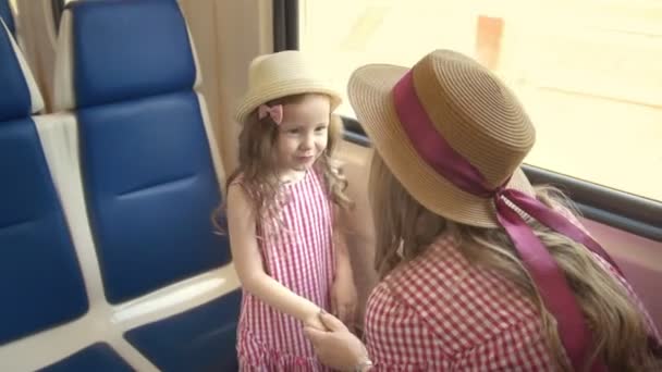 Linda niña viajando junto con su madre - tomados de la mano y hablando en tren cerca de la ventana
 - Metraje, vídeo