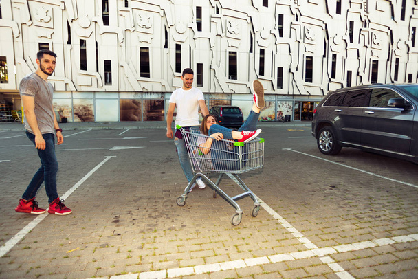 Egy fiatal férfi, egy nő a bevásárlókocsi nyomja teljes hosszúságú portréja - Fotó, kép