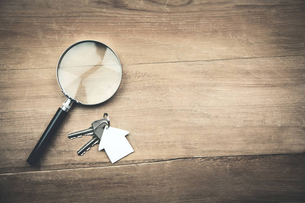 Magnifying glass with house and key on wooden background. - Photo, Image