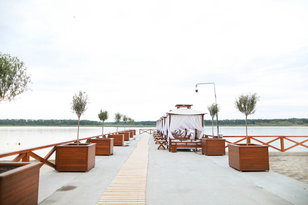 Resort de luxo vazio perto do lago com chaise longues e árvores
. - Foto, Imagem