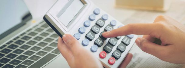 Жінка-бухгалтер або банківський працівник використовує калькулятор в офісі для ділового прибутку і втрат рахунку. Стиль горизонтального веб-банера
. - Фото, зображення