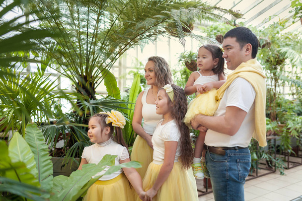 Happy sisters and parents on walk in botanical garden. Girls in yellow skirts, Portrait of large family - Фото, зображення