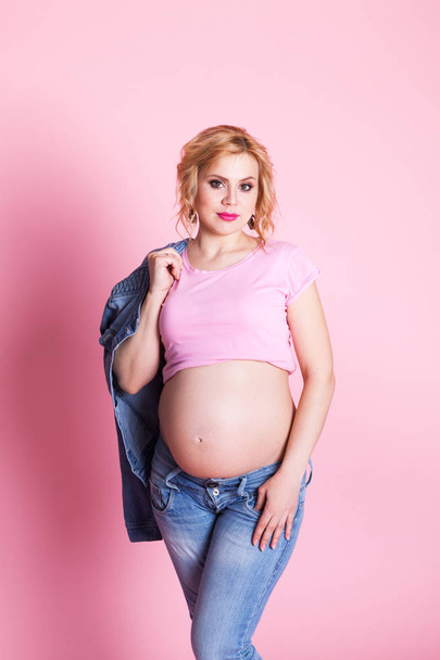 Portrait of beautiful pregnant girl on pink background, indoor - 写真・画像