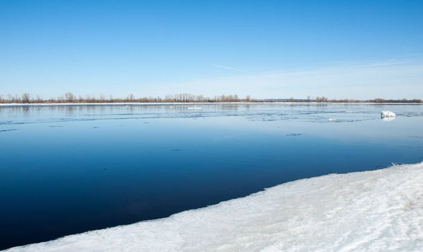 Folyó, tört jég jég hummocks tavasszal a riveren. táj a folyó közeli jégzajlás, a tavaszi, napsütéses napon - Fotó, kép