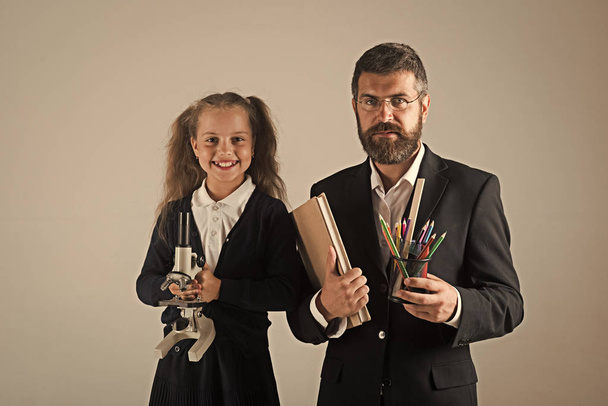 Education and back to school concept. Kid and tutor hold book, pencils and microscope - Valokuva, kuva