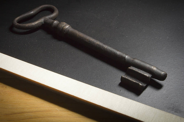 Old rusty key on a black slate - Foto, Imagem