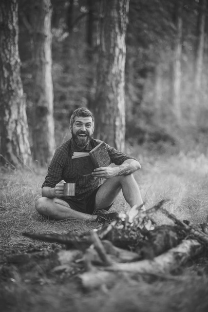 traveler read and drink at campfire flame. Camping, hiking, lifestyle - Zdjęcie, obraz