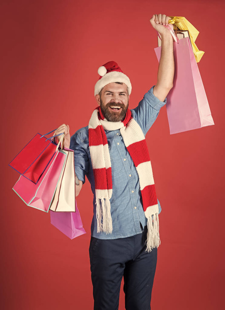 winter sale. Christmas man shopper smile in santa hat with winner gesture - Foto, Imagen