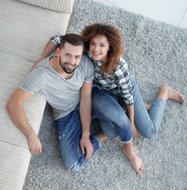 young couple sitting on the carpet in the new living room - Photo, image