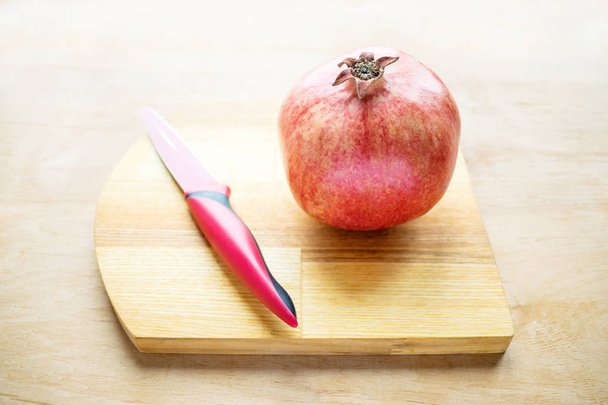 Granatapfel und rotes Messer. wie man einen Granatapfel entkernt. gesundheitliche Vorteile von punica granatum. weiße Schale mit Granatapfelkernen vorhanden. Granatapfel, Granatapfelkerne, Apfel, wilde Trauben - Foto, Bild