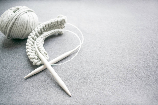 Concept d'aiguille : aiguilles à tricoter, fil de coton gris, a commencé à tricoter sur un fond de feutre foncé. Fil gris boule et aiguilles à tricoter avec espace de copie. Tricot comme une sorte de couture confortable
.  - Photo, image