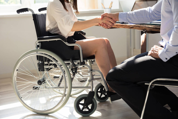 Businesswoman In Wheelchair Shaking Hands With Her Colleague In Office - Foto, immagini