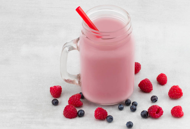Mooie voorgerecht roze frambozen en bosbessen fruit smoothie of milkshake in glazen pot met bessen achtergrond. Yoghurt cocktail. Close-up.  - Foto, afbeelding