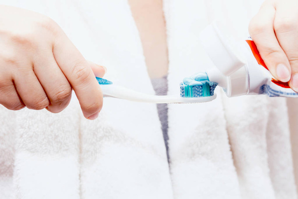 Femme appliquant du dentifrice sur la brosse à dents dans la salle de bain
 - Photo, image
