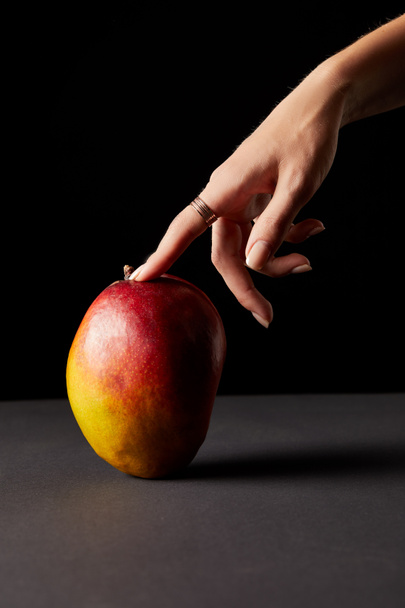 cropped image of woman touching mango on black background  - Valokuva, kuva