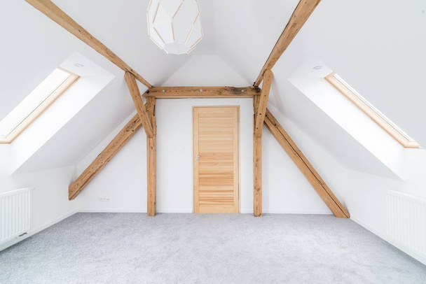 Άδειο δωμάτιο σοφίτα με ξύλινα δοκάρια στην οροφή. Μοντέρνα, φωτεινή σοφίτα διαμέρισμα. - Φωτογραφία, εικόνα