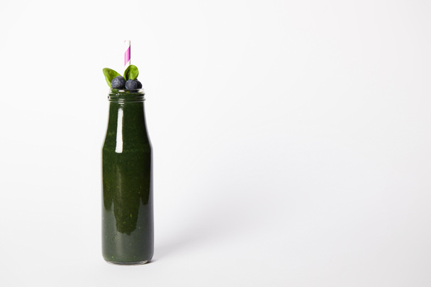 bottle of spirulina smoothie with mint leaves, blueberries and drinking straw on white background  - Фото, изображение