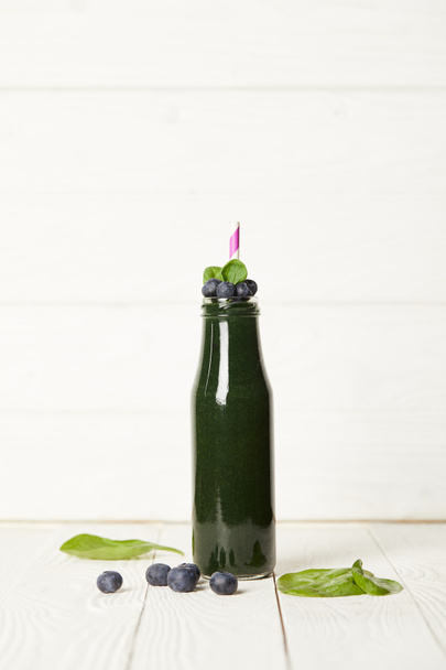 ミントとスピルリナ スムージーのボトルの選択と集中の葉、ブルーベリーと木製のテーブルにストロー  - 写真・画像