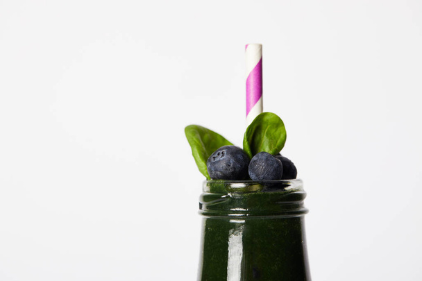 close up view of bottle of spirulina smoothie with mint leaves, blueberries and drinking straw isolated on white background  - Photo, Image