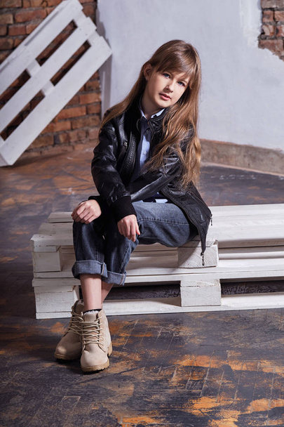 Stylish model child. Beautiful model teen posing against rough brick wall. child fashion concept. teenager wears fashion clothes leather jacket. trendy attractive person girl. - Фото, зображення